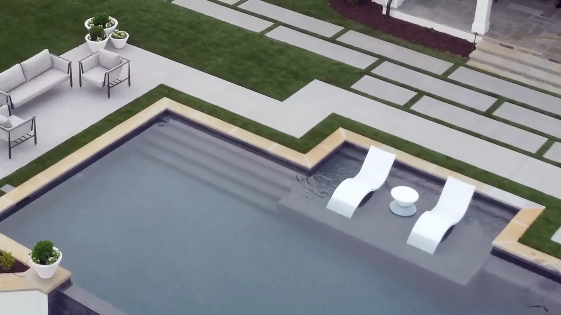 Overhead view of a tanning ledge, large pavers set with turf joints and a pool edge