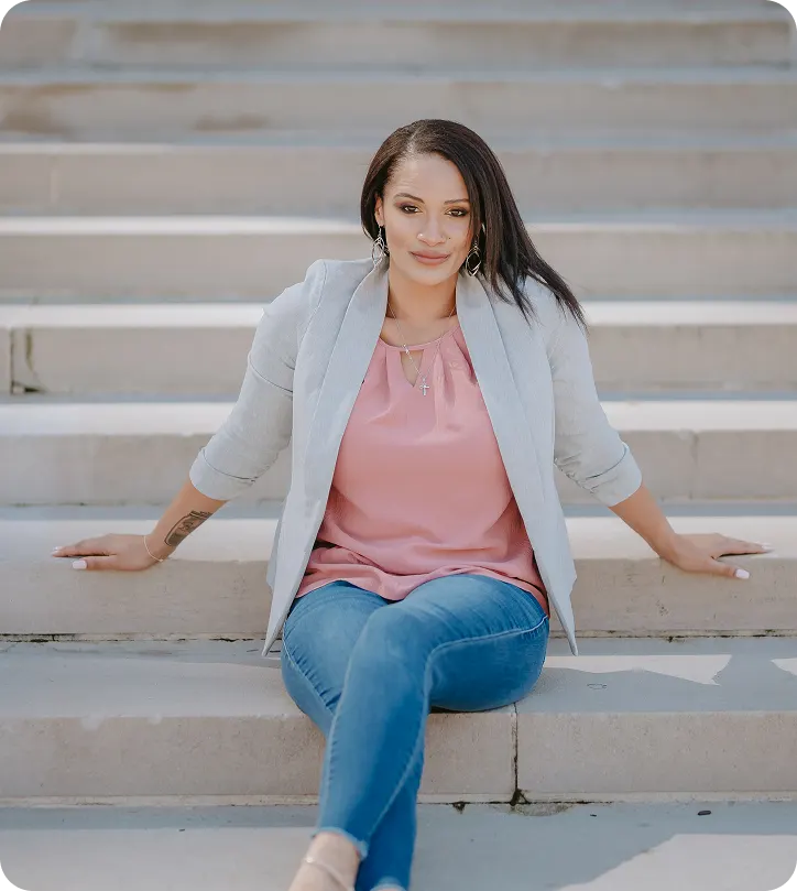 Angela, founder of Angelic Hardscapes & Pools, seated facing the camera on outdoor steps