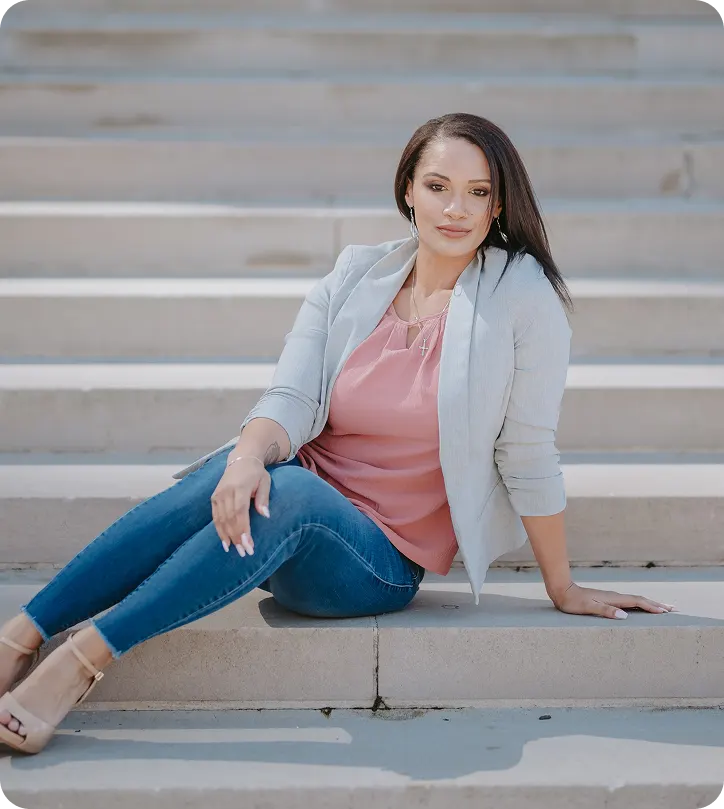Angela, founder of Angelic Hardscapes & Pools, in a gray blazer on stone steps